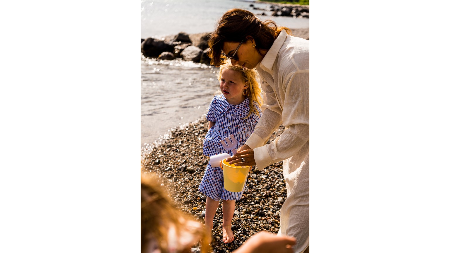 To søde øjeblikke ved stranden med sandet og vandet i baggrunden i varmt sollys.
